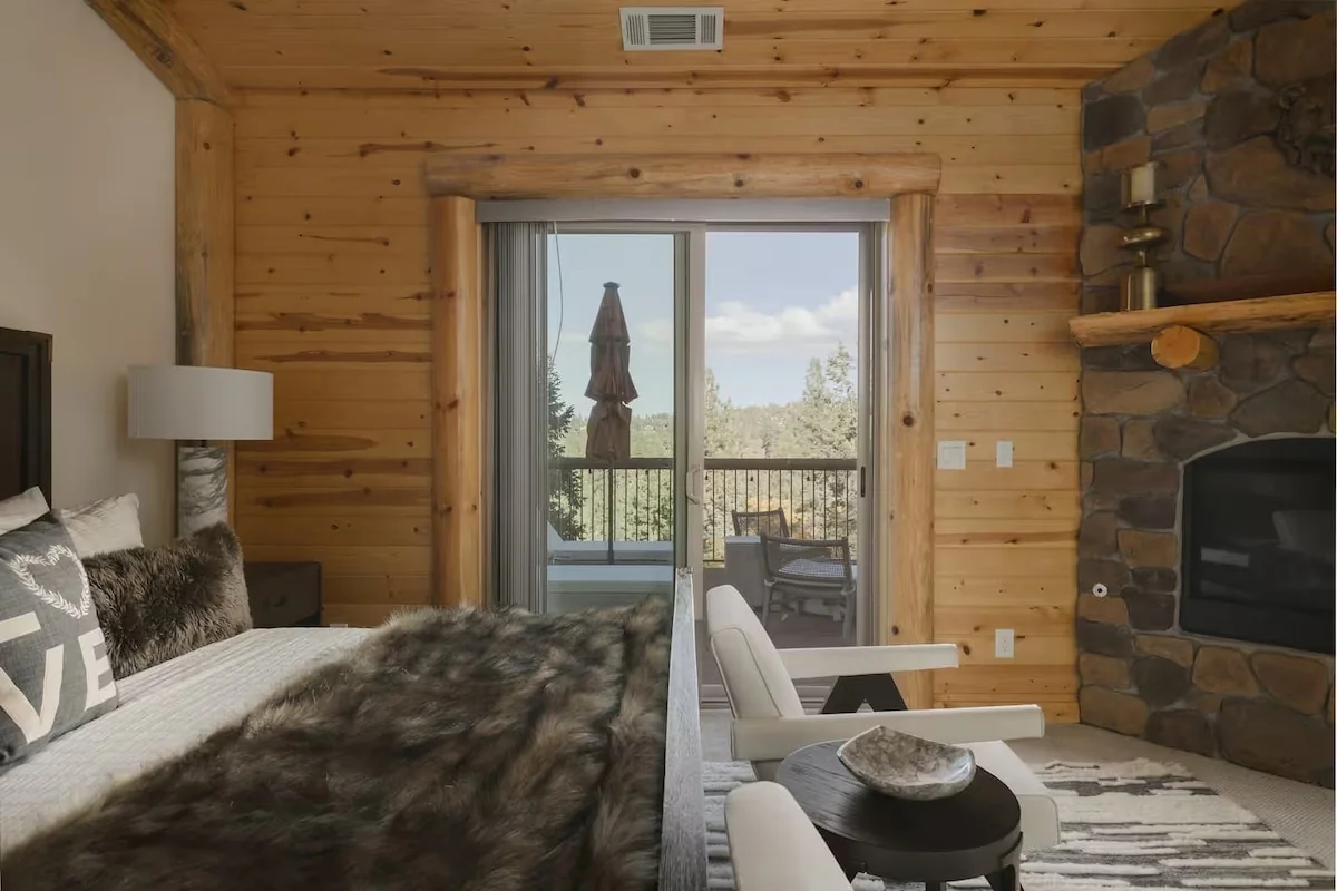 King bedroom with stone fireplace and balcony access